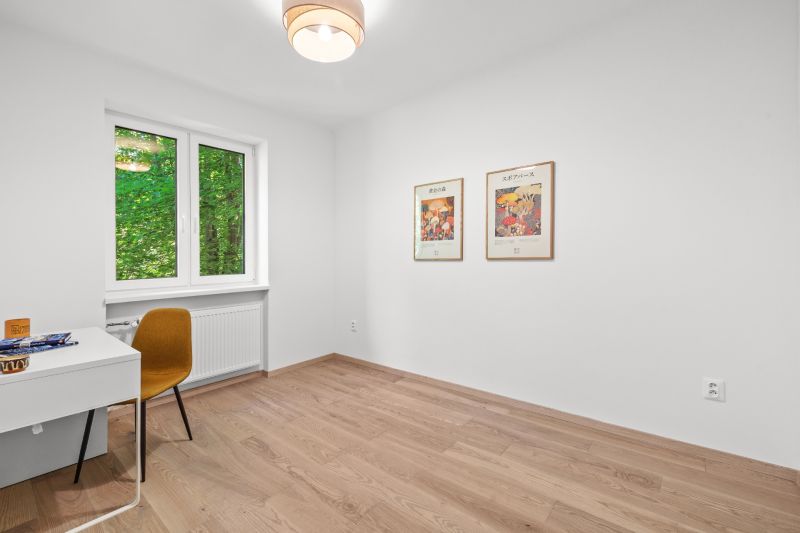 A room in a 3-room apartment with a wooden decor floor and wall paintings.