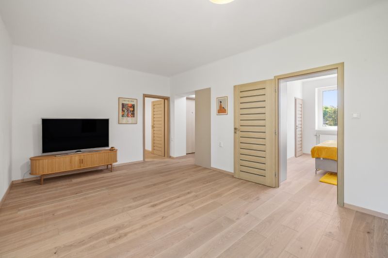 Living room with a television, wooden decor flooring in a 3-room apartment.
