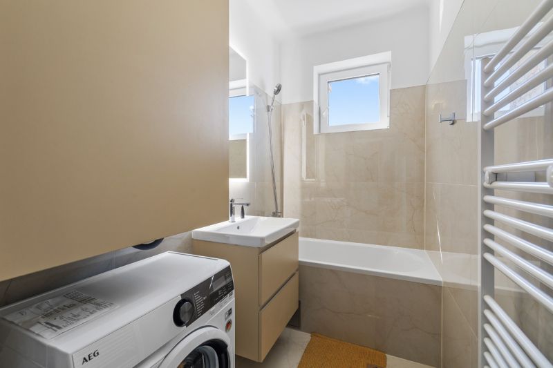 Bathroom with a bathtub, washing machine, and sink in a 3-room apartment.