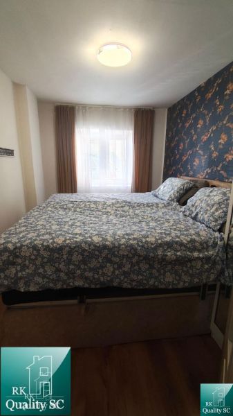 A bedroom in a family house with floral wallpaper and a wooden decor floor.