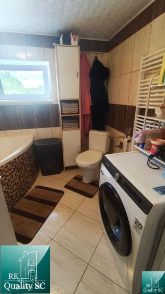 Bathroom in a family house with a bathtub, washing machine, and storage space.