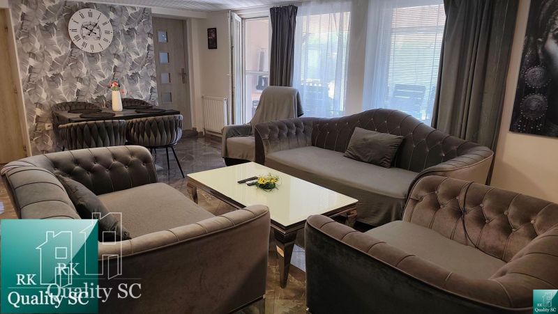 Living room in a family house with comfortable sofas, a dining table, and decorative curtains.