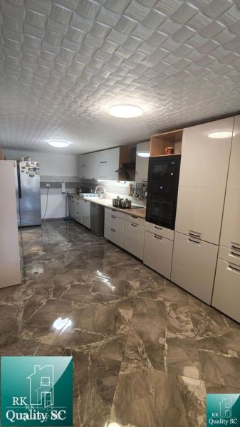 A kitchen with a glossy floor, white cabinets, and appliances in a family house.