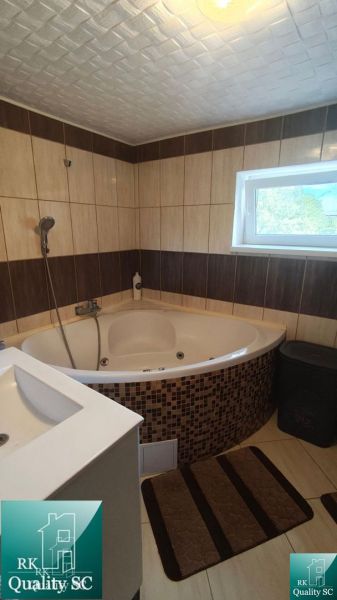 A bathroom in a family house with a corner bathtub and tiles in a wood decor.
