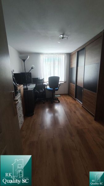 A home office with a wood-patterned floor and a large wardrobe in a family house.