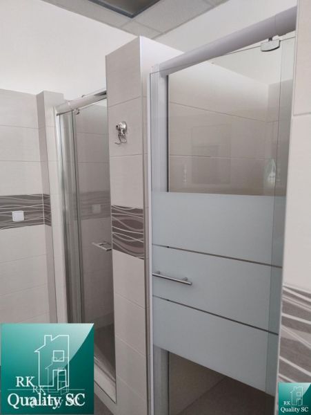 Bathroom in production premises with ceramic tiles and a shower enclosure.