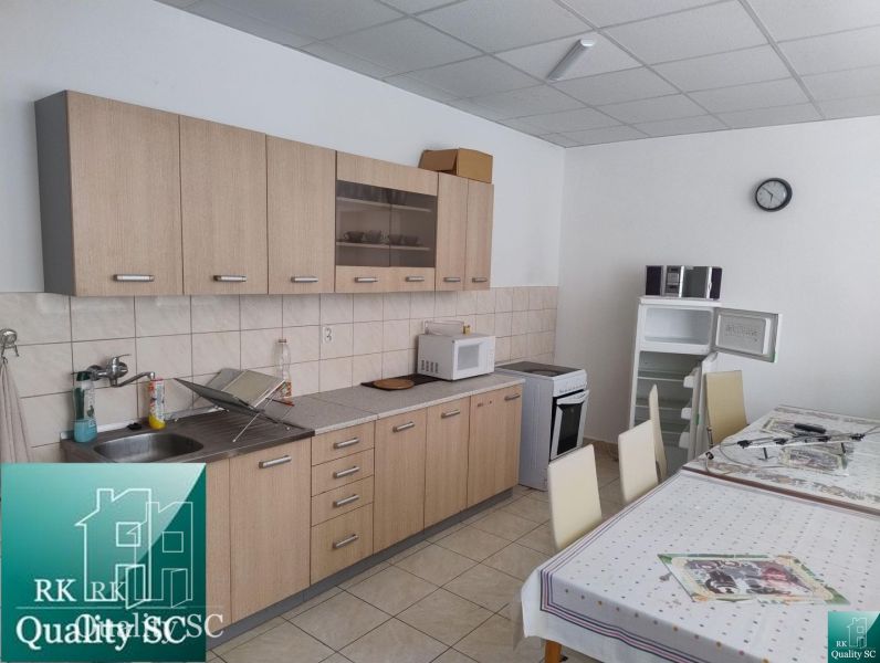 A kitchen unit in a production area with a wooden decor floor and a table with a tablecloth.