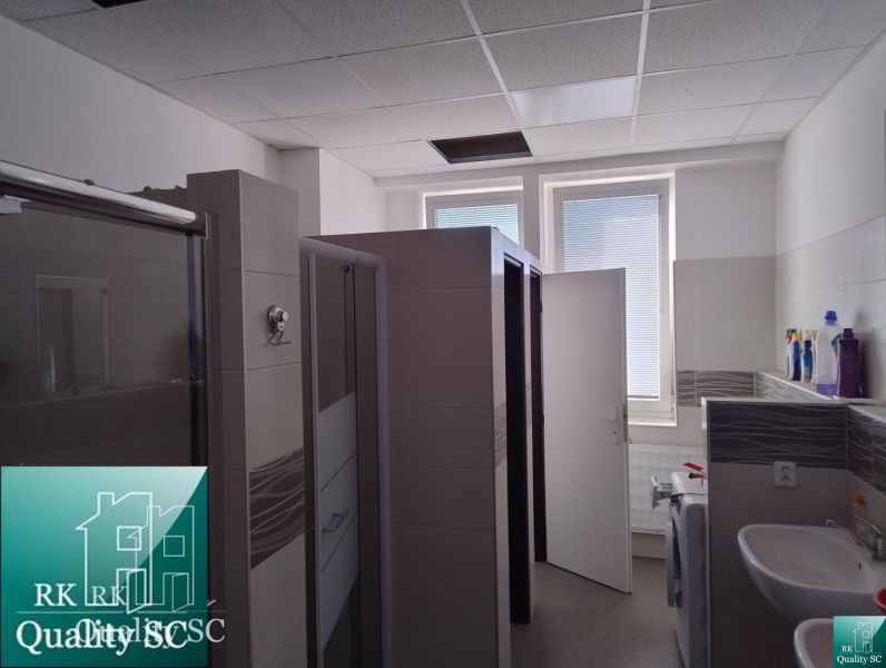 Bathroom with shower stalls and a sink in warehouse and hall spaces.