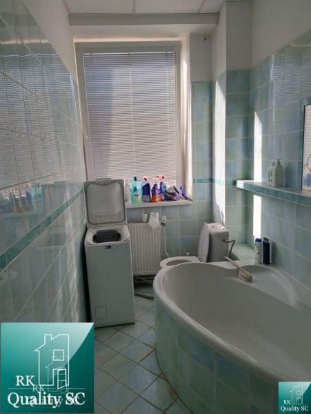 Bathroom with a bathtub, washing machine, and cleaning products in indoor storage and halls.