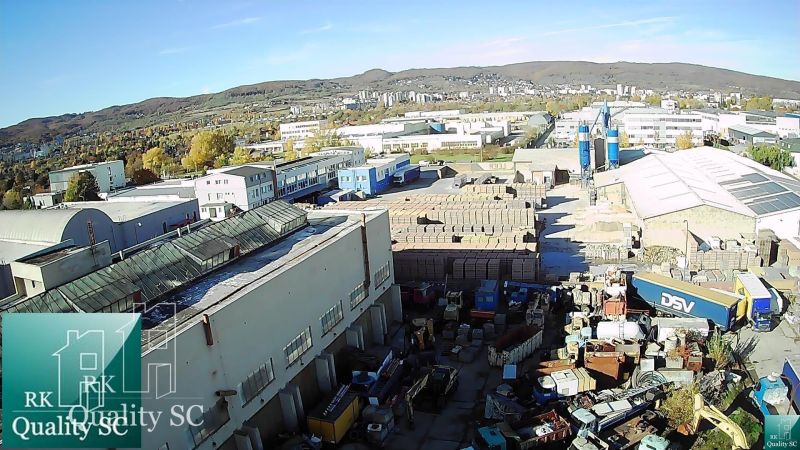 A view of warehouses and halls on Staviteľská Street in Bratislava III surrounded by trucks and materials.