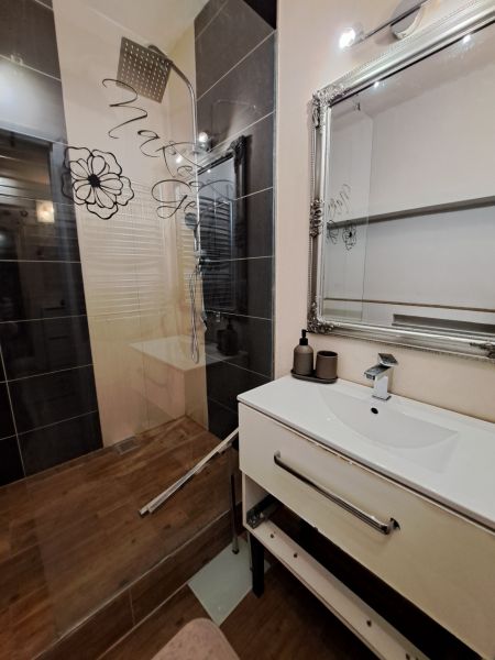 A bathroom in a 3-room apartment with a decorative mirror and a shower corner.