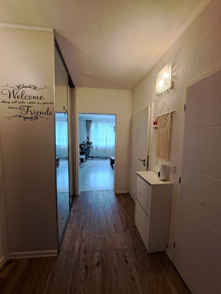 Interior of a 3-room apartment with a wooden decor floor and light furniture.