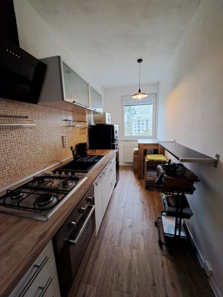 A kitchen with a wooden decor floor and a view, furnished in a 3-room apartment.