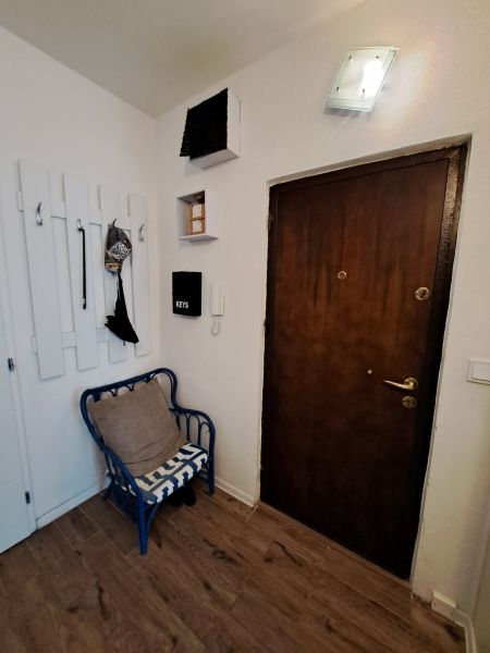 The space in the three-room apartment has a floor with a wooden decor and a hanging coat rack.