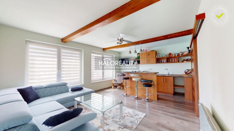 Living room in a family house with a kitchen, wooden decor flooring, and comfortable seating.