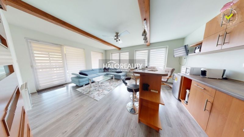 Living room in a family house with a wooden decor floor, sofa, and kitchen counter.