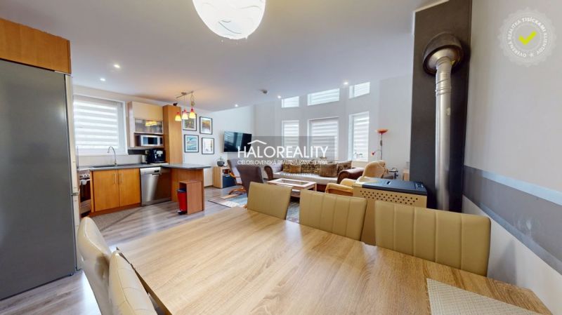 A spacious kitchen in a family house with a wood-patterned floor and modern furniture.