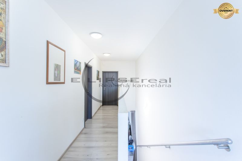 A hallway with light walls, doors, and a floor with a wooden decor in a family house.