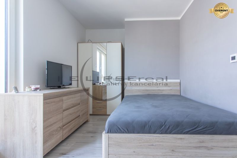 A bedroom with a wood-patterned floor, a wardrobe, a dresser, and a television.