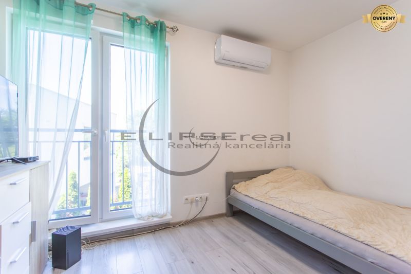 A room with a bed, air conditioning, and a wooden decor floor in a family house.