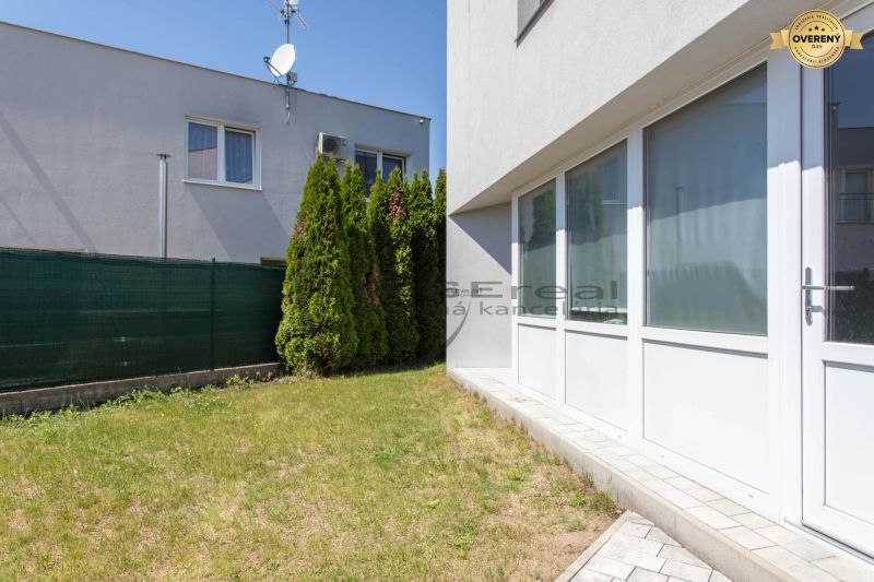 A family house in Stupava with a grassy yard and a hedge.
