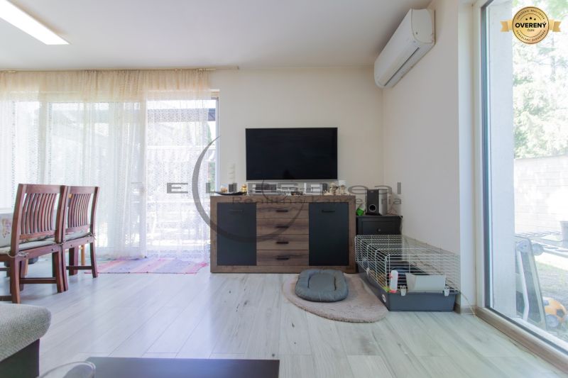 Living room in a family house with a television, a cage, and a floor with a wooden decor.