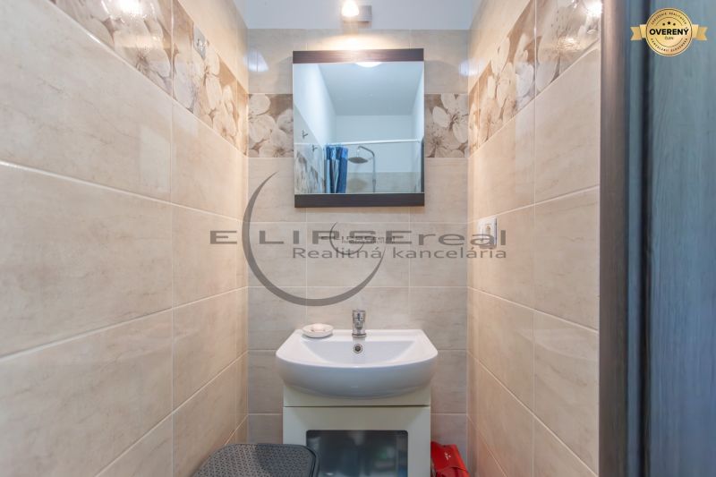 A small bathroom in a family house with a sink, a mirror, and floral tiles.