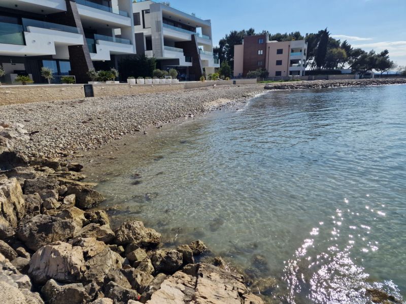 The coast near three-story buildings in Sukošan, ideal for a three-bedroom apartment with a view.