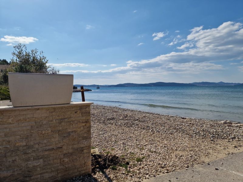 A sandy beach with pebbles and a view of the sea near Sukošan.