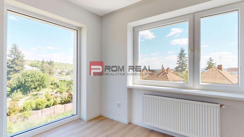A room with large windows, a view, and a wooden decor floor in a family house.
