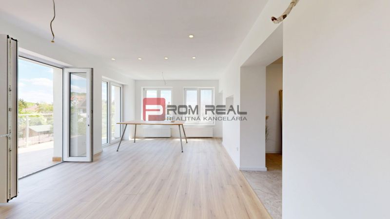 Interior of a family house with a wooden-patterned floor and large windows.