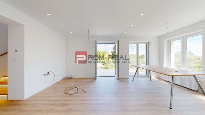 The interior of a family house with a wooden decor floor, large windows, and a table.