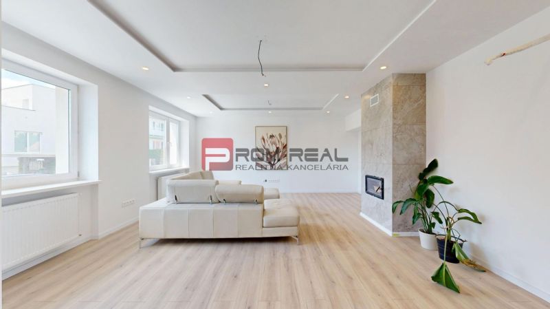 Living room in a family house with a wooden decor floor, fireplace, and large windows.