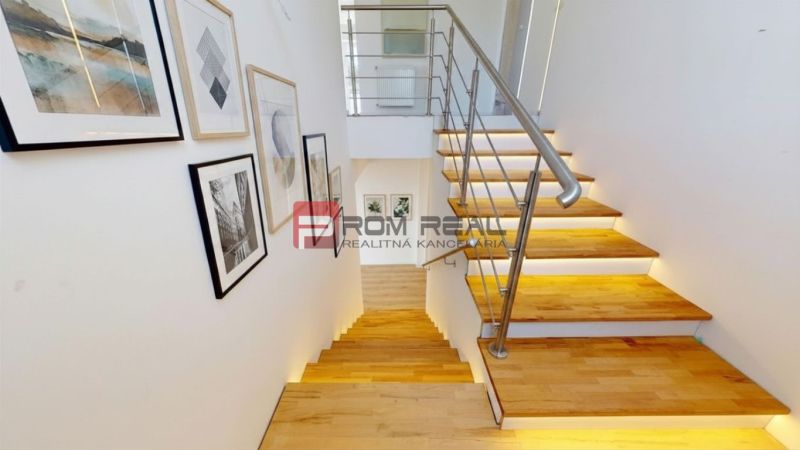 A staircase with a wooden decor floor in a family house, adorned with paintings.