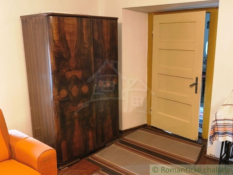 A wooden cabinet by the door and an orange couch in the cabin.