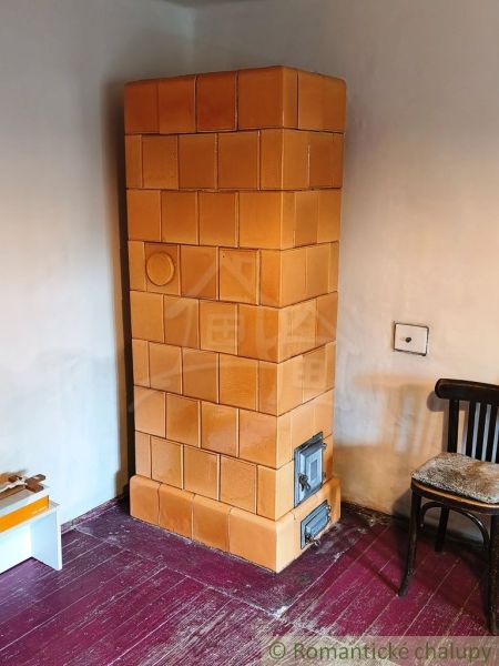 Tiled stove, wooden chair, and floor with wooden decor in the cabin.