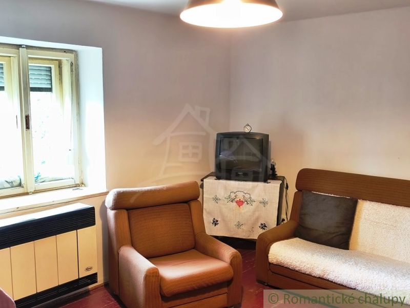 Living room in a cottage with armchairs, a television, and traditional decorations.