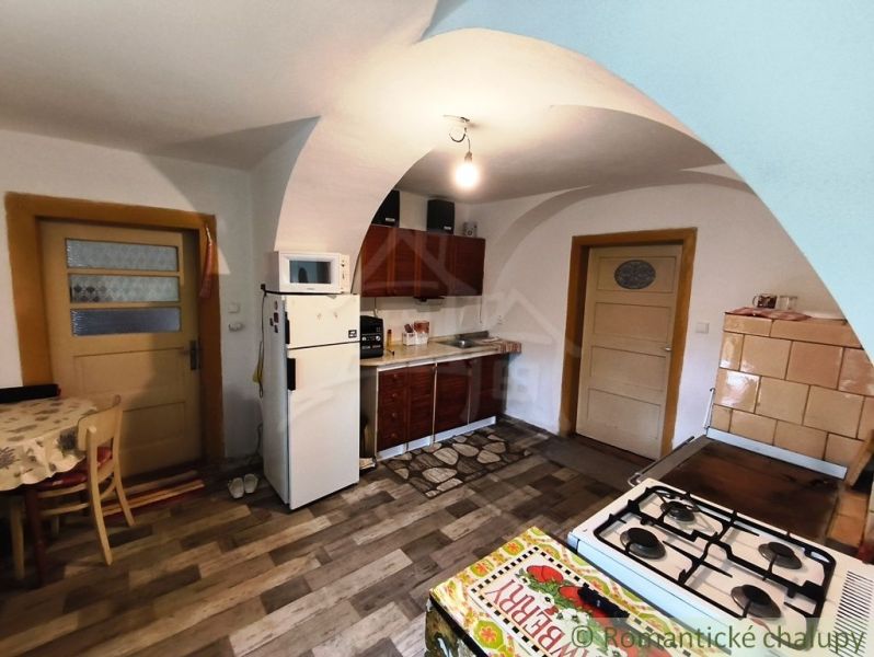 A kitchen in a cottage with a wooden decor floor and a tiled stove.