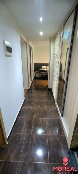 A hallway in a 3-room apartment with glossy tiles and a mirrored wardrobe.