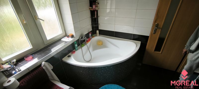 A bathroom with a separate bathtub in a 3-room apartment, complemented by black tiles.