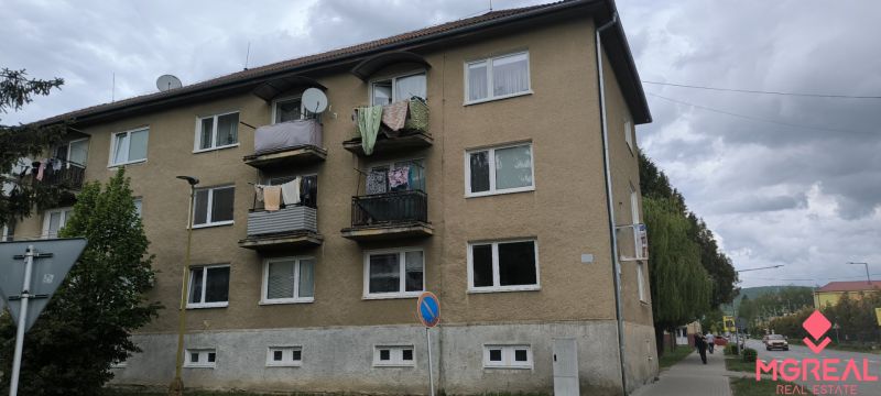 An apartment building in Snina with balconies and drying laundry, located by the street.