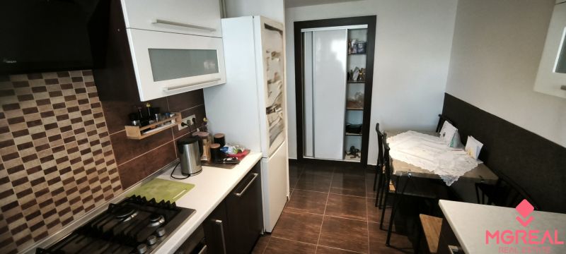 Kitchen in a 3-room apartment with a cooktop, dining table, and floor with a wooden decor.