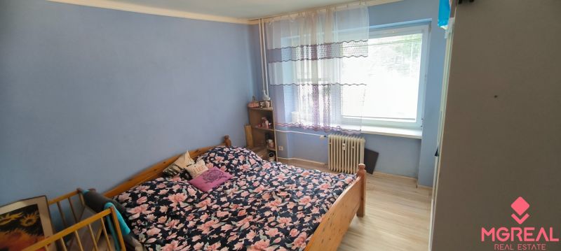 A bedroom in a 3-room apartment with floral bed linen and a wooden decor floor.
