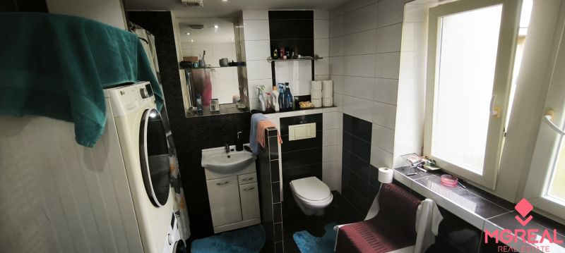 A bathroom in a 3-room apartment with black and white tiles, a washing machine, and a window.