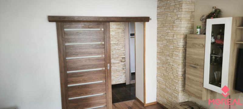 Interior of a 3-room apartment with sliding doors and decorative stone cladding.