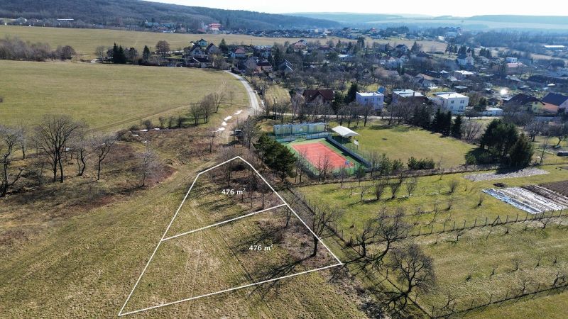 A plot for residential purposes in Hodkovce surrounded by greenery and a tennis court.