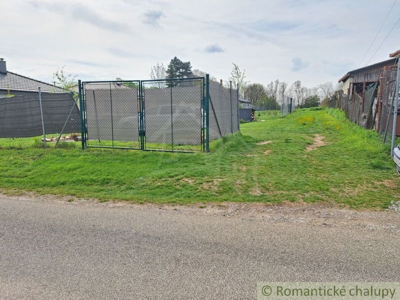 Gardens in Hruboňovo with an access road and fencing.