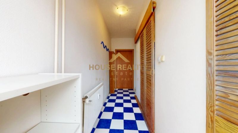 A narrow hallway with a blue and white checkered floor and a wardrobe in a studio apartment.