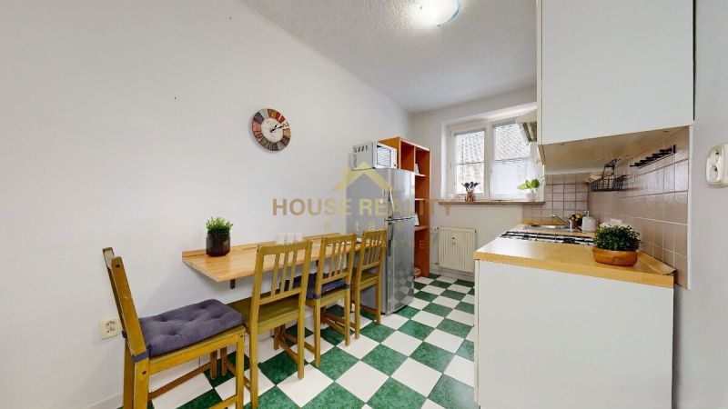 A kitchen in a studio apartment with a dining area, linoleum flooring, and appliances.