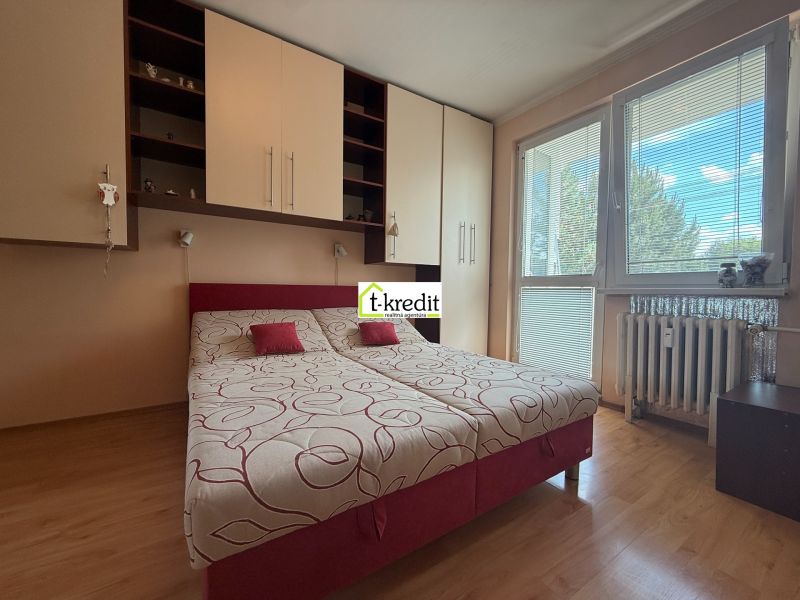 A room in a 3-room apartment with a bed, built-in wardrobes, and a floor with a wood decor.